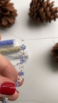 a woman is making beaded bracelets with pine cones on the table behind her