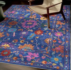 a blue rug with colorful flowers on it and a chair in the corner next to it