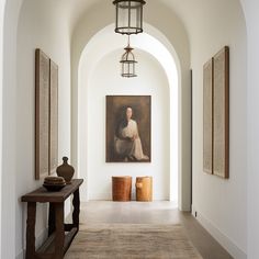 a hallway with a painting on the wall and two vases in front of it