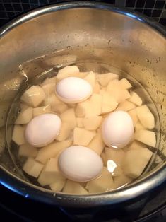 four eggs are in a pot with water on the stove top, ready to be cooked