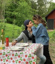 two people sitting at a table with plates and wine bottles in front of them,