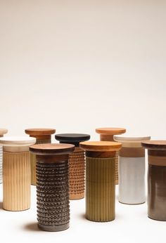 a group of different colored vases sitting next to each other on a white surface