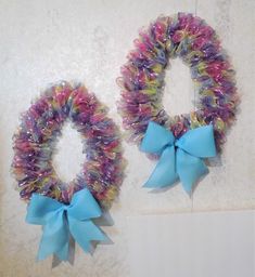 two wreaths with blue bows hanging on the wall