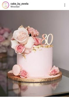 a pink cake with flowers and the number 80 on it is sitting on a table