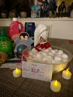 an elf is sitting in a bathtub full of soap balls and candles with a sign that says have e l f u spa day