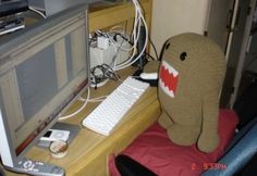 a stuffed animal sitting in front of a computer monitor on a desk next to a keyboard and mouse