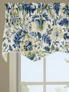 a window with a blue and white floral curtain hanging from it's valance