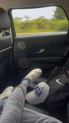 a person sitting in the passenger seat of a car with their feet propped up on the steering wheel