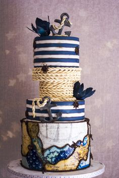 a three tiered cake decorated with blue and white stripes, nautical decorations and birds