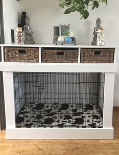 a white dog crate with two baskets on top and a plant in the corner next to it