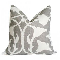 a gray and white pillow with an intricate design on the front, sitting against a white background