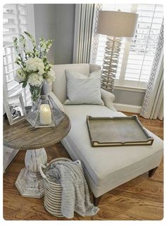 a living room filled with furniture and flowers on top of a coffee table in front of a window