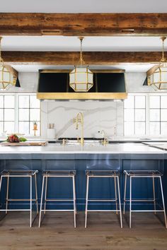 a large kitchen with blue cabinets and gold accents on the countertops, along with bar stools