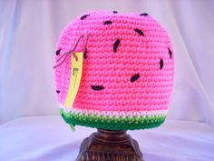 a crocheted watermelon hat on top of a wooden base with a price tag