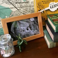 some books are sitting on a table next to a glass jar with a small toy