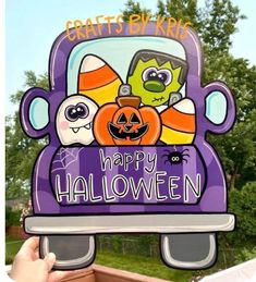 a person holding up a purple truck with halloween decorations on it's front window