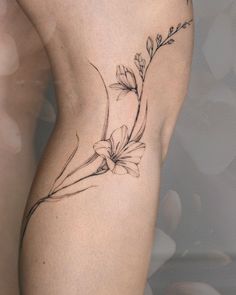 a woman's thigh with a flower tattoo on her left side ribcage