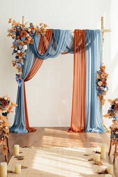 a decorated stage with blue and orange drapes, candles and flowers on the floor