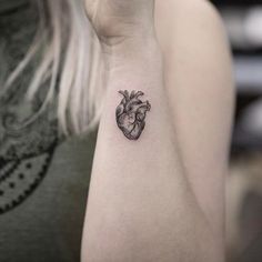 a small heart tattoo on the right arm and shoulder, with an arrow in the middle