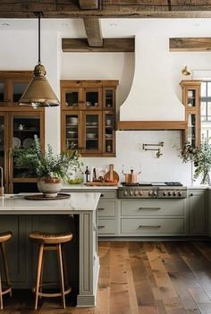 a large kitchen with wooden floors and green cabinetry on the walls, along with two bar stools