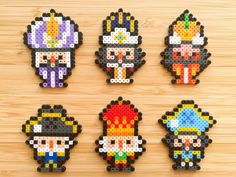 four pixel art pieces are arranged on a wooden surface, each with different characters and colors