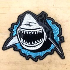 a patch with a shark on it that has been embroidered onto the side of a wooden surface