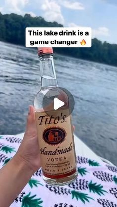 someone is holding up a bottle of alcohol in front of the water and text reads, this lake drink is a game changer