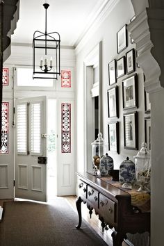 an entry way with pictures on the wall and a lamp hanging from the ceiling above it