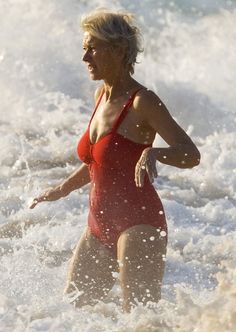 a woman in a red swimsuit running into the ocean