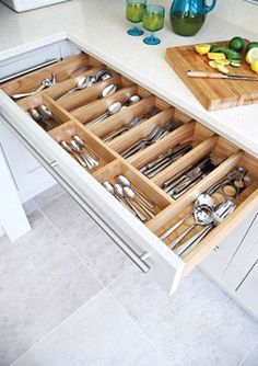 an open drawer in the middle of a kitchen with utensils and spoons