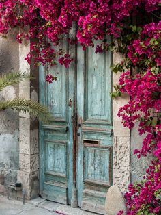 an old blue door with pink flowers growing over it