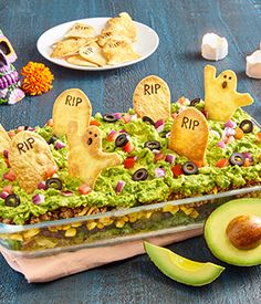 a dish with guacamole, chips and ghost decorations