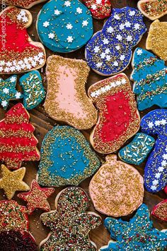 many decorated cookies are on a wooden surface with glittery stars and snowflakes