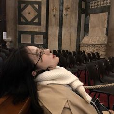 a woman with long black hair laying on a bench in front of an empty auditorium