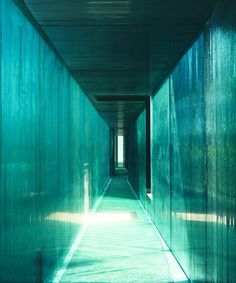 a long hallway with green walls and light at the end