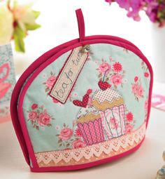 a pink and blue purse with cupcakes on it sitting next to some flowers