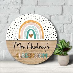 a wooden sign with the name mrs audrey's classroom next to a potted plant