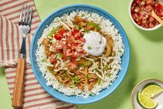 a blue plate topped with rice and meat next to a bowl of sour cream sauce