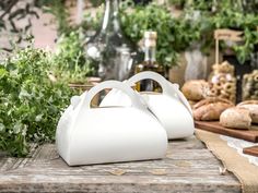 two white purses sitting on top of a wooden table next to bread and vegetables