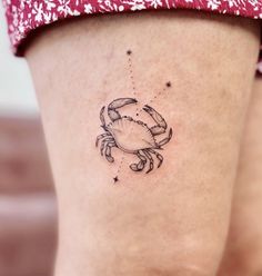 a woman's thigh with a small tattoo of a crab and stars on it