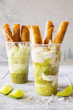 two cups filled with food and garnished with lime wedges next to each other