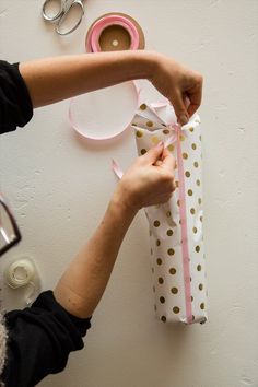 a person wrapping a gift with pink and gold polka dots