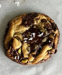 a chocolate chip cookie sitting on top of a piece of wax paper with white flakes