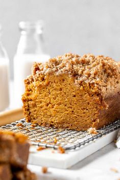 a loaf of pumpkin bread sitting on top of a cooling rack next to milk bottles