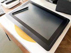 a tablet computer sitting on top of a desk next to a pen and laptop keyboard