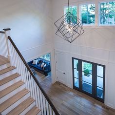 an open floor plan with white walls and wood floors, two chandeliers hanging from the ceiling