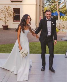 a bride and groom holding hands in front of a building