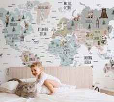 a little boy that is laying down on a bed with a cat in front of him