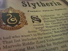 a close up of a book with an image of slytherin on the page