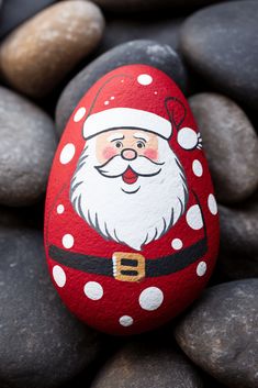 a painted rock with a santa clause on it sitting among some black and white rocks